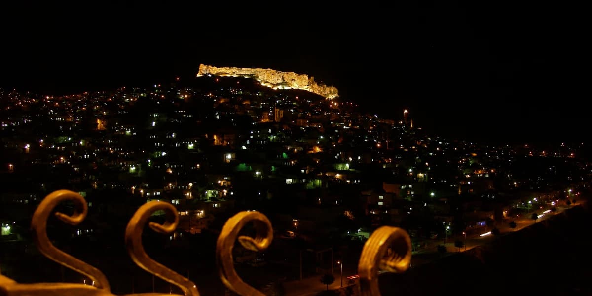 Gece Mardin yamacında parıldayan şehir ışıkları ve aydınlatılmış kale