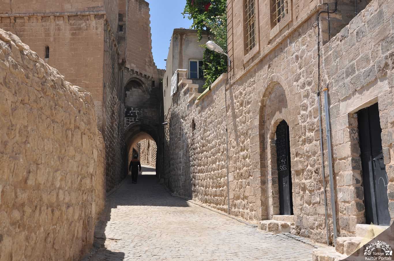 Mardin taş sokaklarında tek yönlü kıvrılan dar yol ve taş cepheler